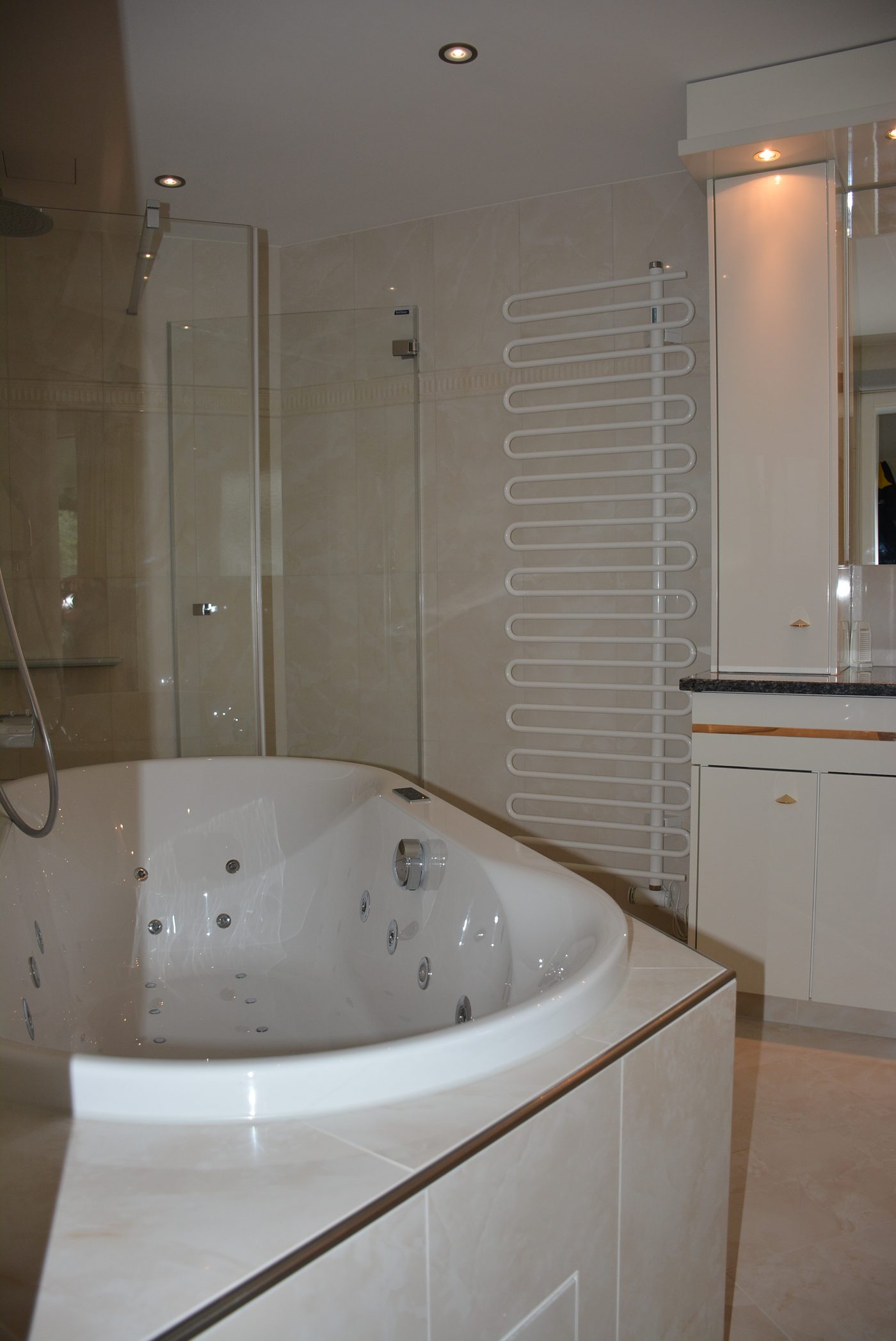 Badezimmer mit Whirlwanne, Handtuchheizkörper und Glasdusche