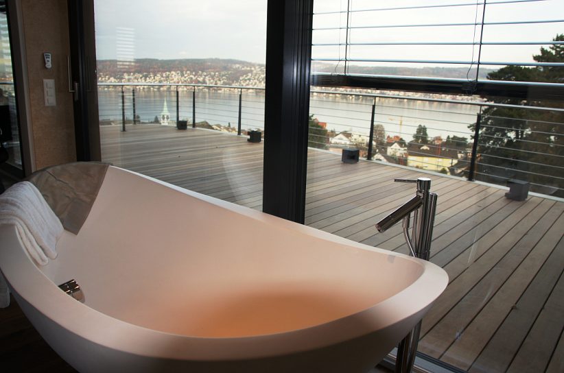 Freistehende Badewanne auf einer Terrasse mit Blick auf den See